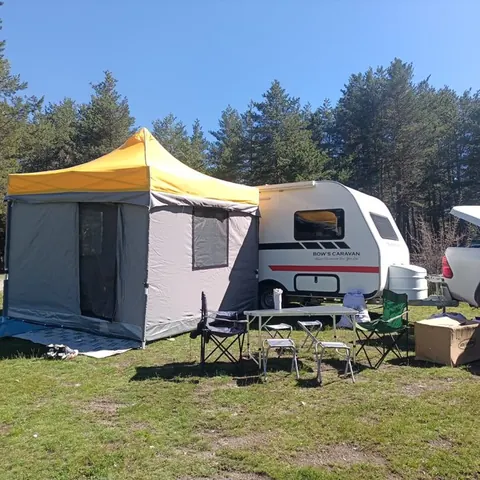 Çam ormanında karavan yanında sarı gri gazebo çadır