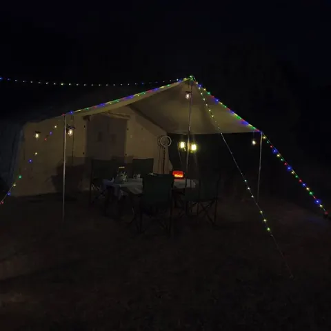 Gece ışıklarla süslenmiş kamp çadırı ve tente