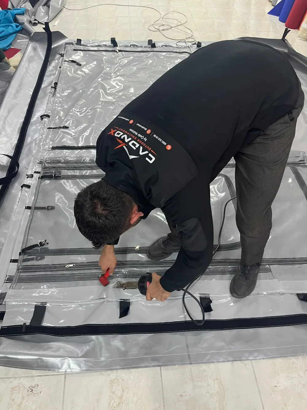 CADNOX ustası şeffaf PVC çadır panelinin fermuarlı eklerini sıcak hava kaynağıyla birleştiriyor