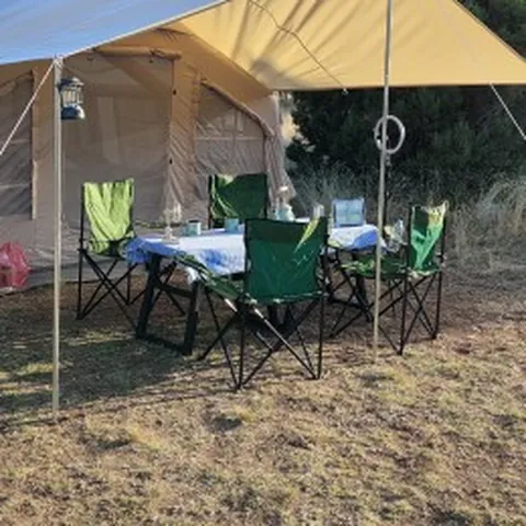 Tenteli kamp çadırı önünde kamp masası ve sandalyeler